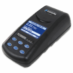 A black handheld turbidity meter, labeled “TC3000i TR-METER,” features a digital screen with measurement data and navigation buttons. This LaMotte device is part of the TC3000i BLE Meter - 1976-I series.