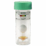 Un flacon en plastique transparent avec un couvercle vert, contenant une boule sur un bâton et un liquide orange au fond. L’étiquette indique Bactéries Formatrices de Slime - SLYM-BART - 5-0026 avec un tableau codé par couleur et un indicateur jours à aujourd’hui.