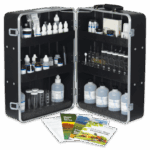 A black carrying case open to reveal bottles, vials, test tubes, and droppers organized on foam shelves, with booklets and manuals placed in front of the Model STH-14 - Soil Testing Outfit.