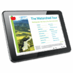 A tablet displays a digital document titled “The Watershed Tour - 5974: Setting Up The Tour | For the Instructor,” featuring a menu on the right and a photo of a river winding through green mountains on the left.